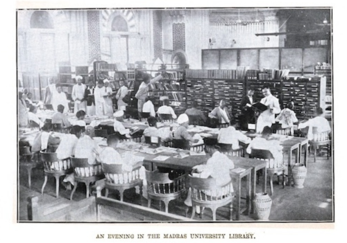 In this black and white photo, students sit around long tables in the madras university library.